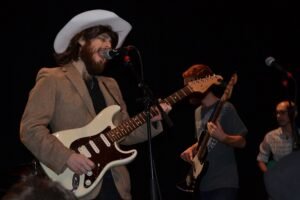 Zachary Drummond singing and playing electric guitar during a live band performance.