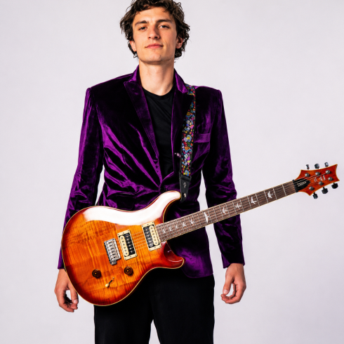 Malikhai Walton holding an electric guitar during a professional studio portrait for guitar, piano, bass, and ukulele lessons in San Diego.